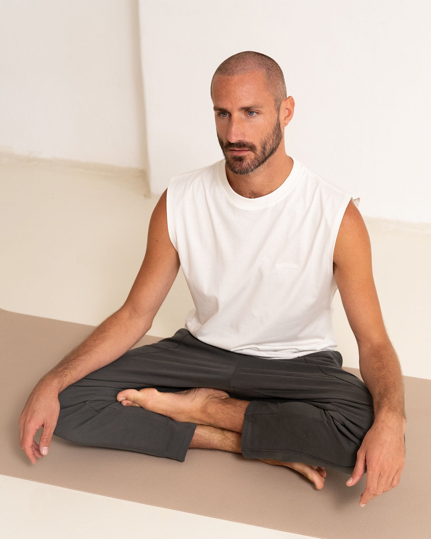 Marshmallow - Male Model sitz im Schneidersitz in Yoga Tanktop