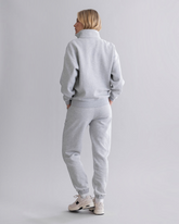 Rückansicht einer Frau in grauer greenyogashop Sweatpants mit elastischen Bündchen und passendem Sweatshirt