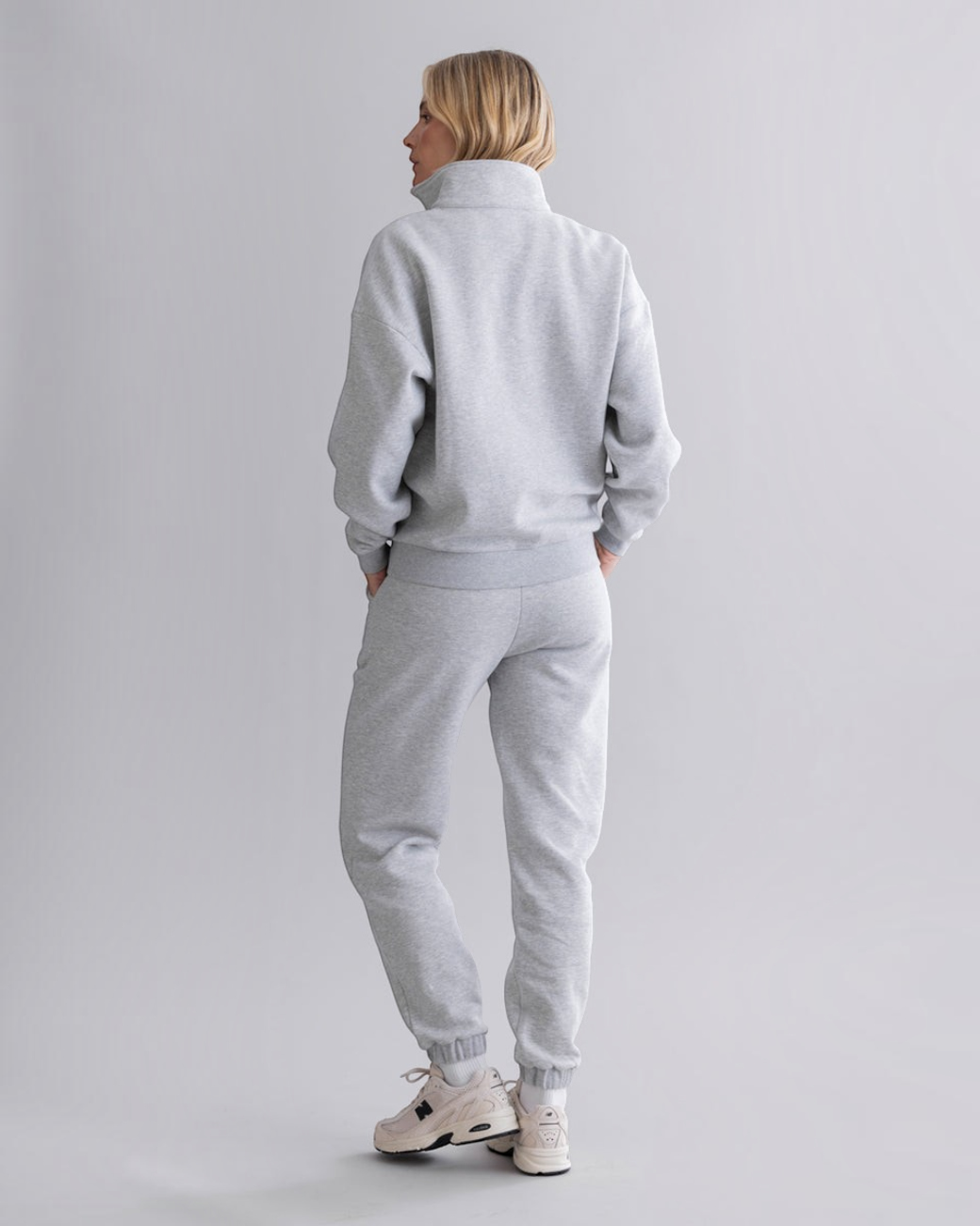 Rückansicht einer Frau in grauer greenyogashop Sweatpants mit elastischen Bündchen und passendem Sweatshirt