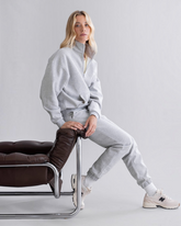 greenyogashop Cuff Sweatpants in Grau Melange mit elastischen Bündchen, getragen von einem Model auf einem Sessel