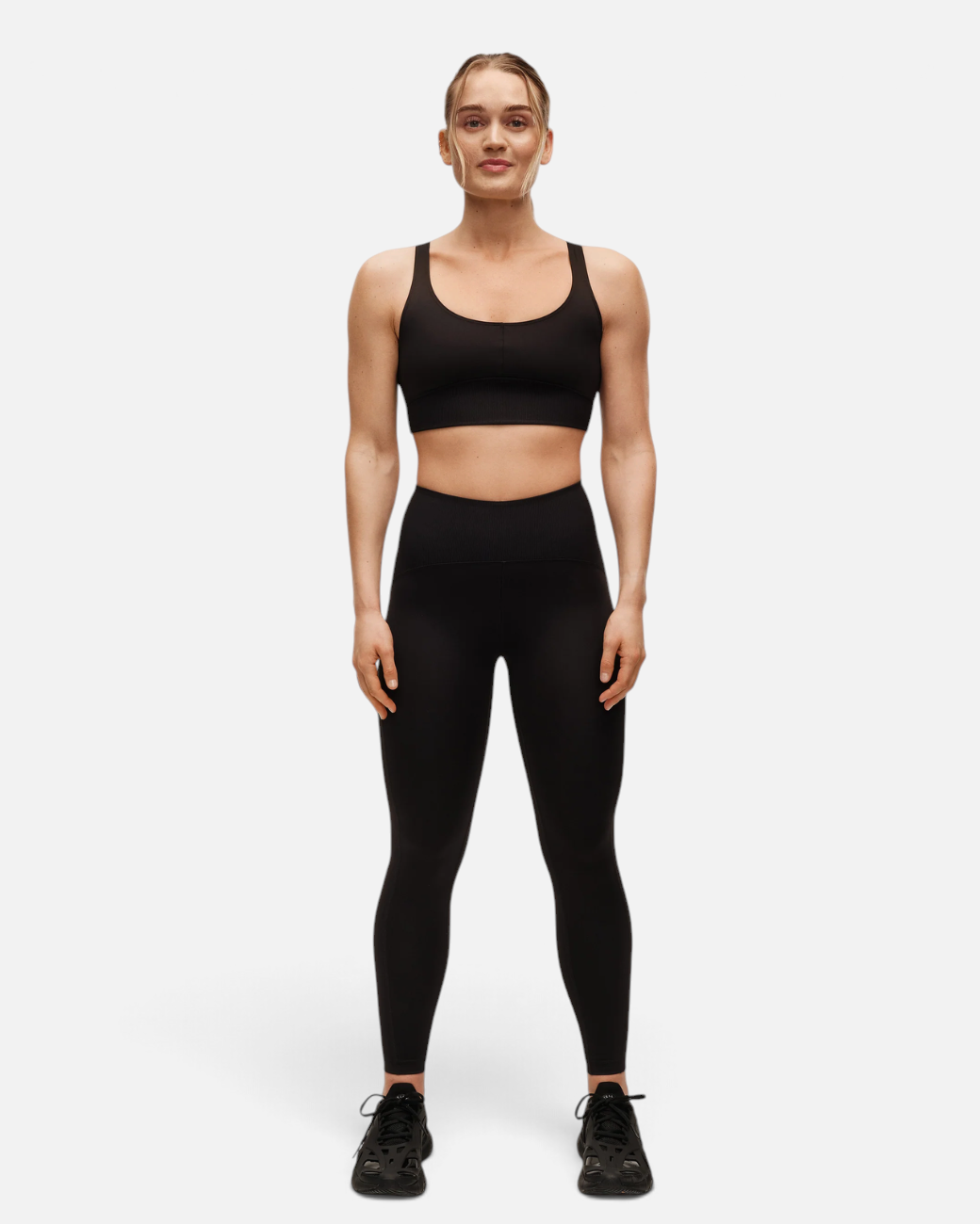 Sportlerin in schwarzen Brace Rib High Waist Leggings von greenyogashop mit geripptem Bund und figurbetonter Passform
