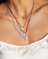 greenyogashop Sternzeichen Kette Steinbock aus Sterlingsilber mit Rubin an farbiger Schnur am Hals getragen