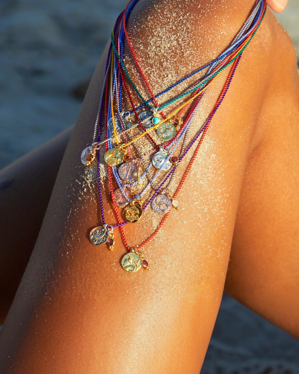 greenyogashop Sternzeichen Ketten mit Amuletten aus Sterlingsilber und Rosenquarz auf sonnengebräunter Haut am Strand