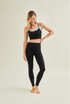Woman wearing a black sports bra and high-waisted circular leggings by Wellicious, showcasing toxin-free and microplastic-free fabric