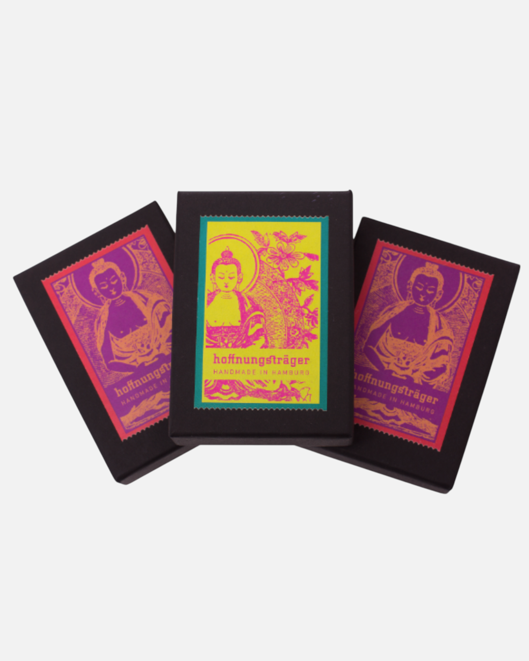 Drei schwarze Geschenkboxen von greenyogashop mit buntem Buddha-Druck für den Mantra Armreif